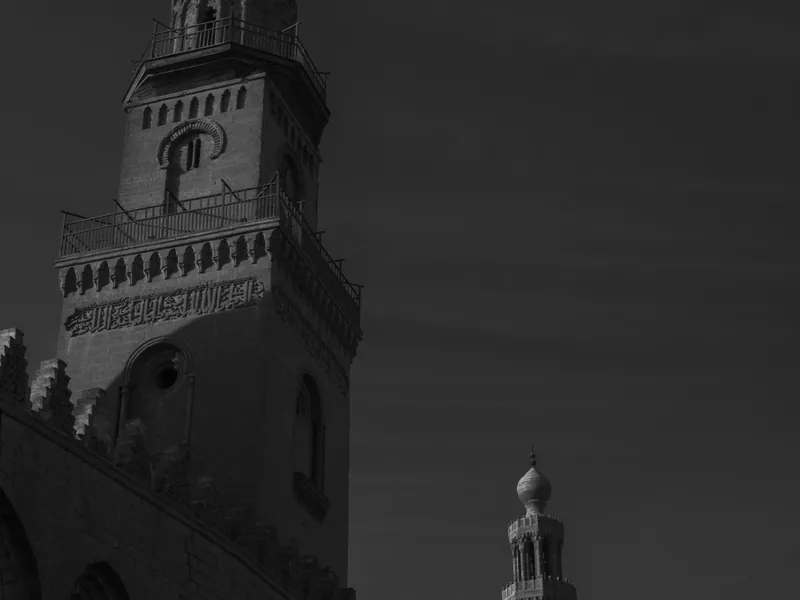 A minaret rising over Cairo rooftops in high contrast black and white
