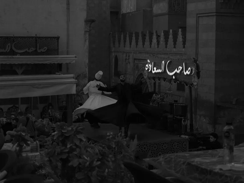 Black and white interior of a Cairo cafe, Arabic signage on the wall above the tables