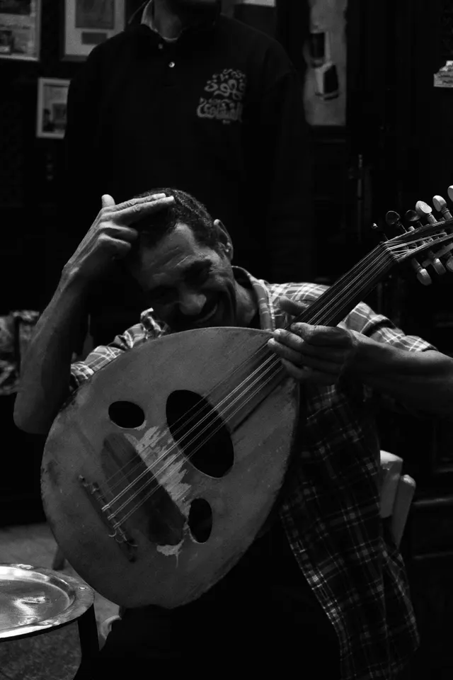 A musician playing an oud on the street, black and white