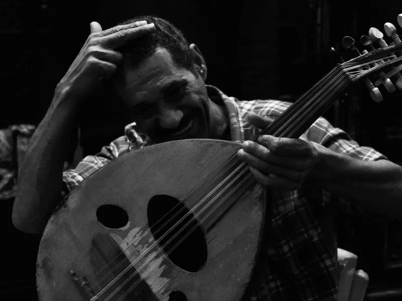 A musician playing an oud on the street, black and white