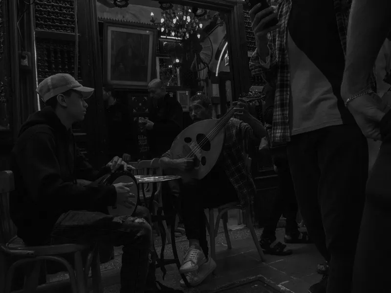 Black and white street market interior, figures moving between stalls in low light