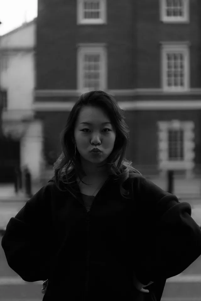 A woman in a black jacket standing in front of a red brick building