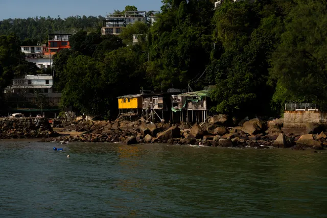 A bay with houses stacked up the green hillside above the water