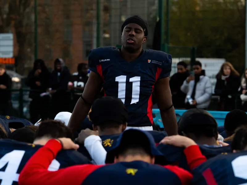 A player in a number eleven jersey standing among teammates on the sideline