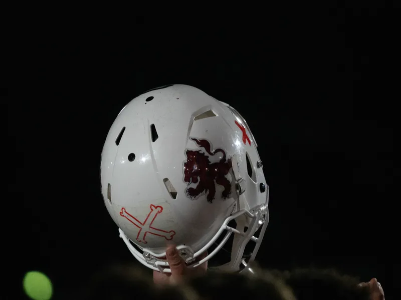 A scuffed white helmet held up, catching the last of the light