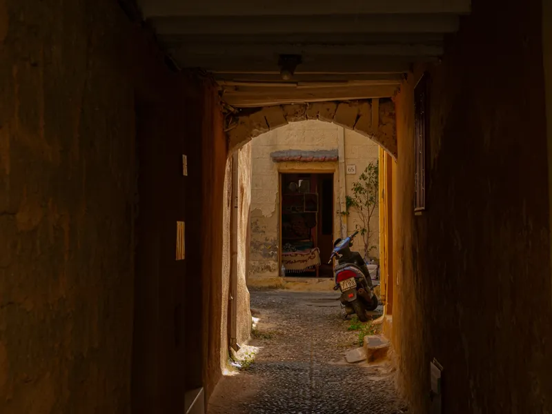 A dark corridor opening onto a lit doorway at the far end