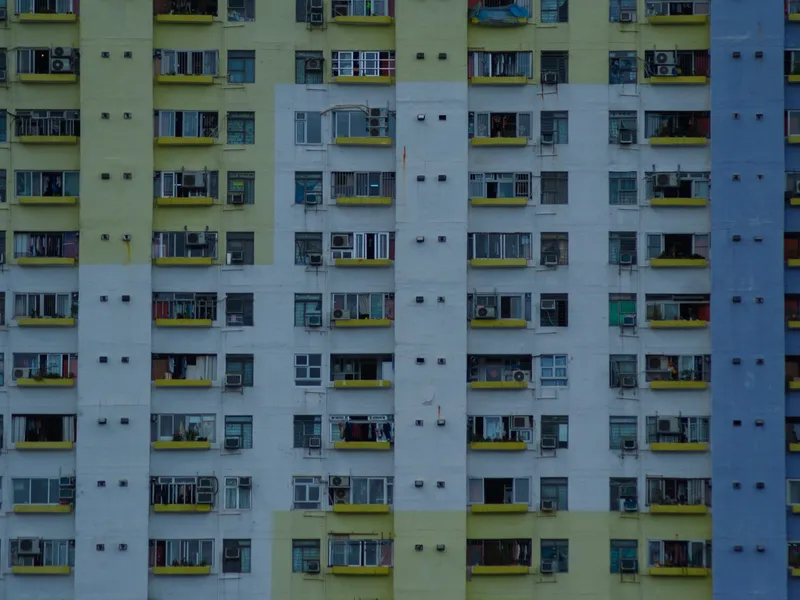 A yellow and green apartment block, laundry and air units on every floor