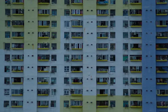 A yellow and green apartment block, laundry and air units on every floor