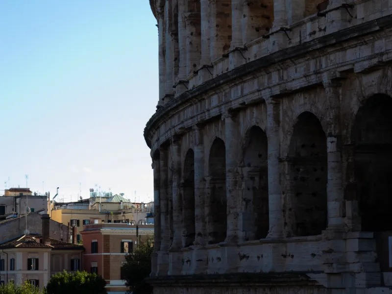 The outer arches of the Colosseum against a clear blue sky