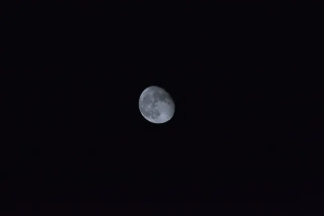 The moon bright and small in an otherwise black sky