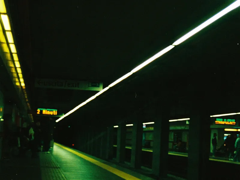 An empty station platform lit green, shot on film