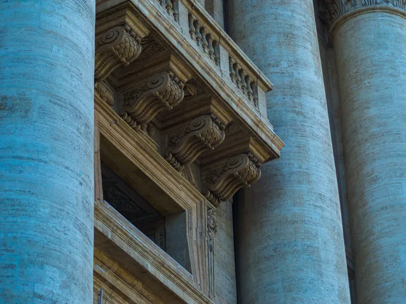 Looking up the pale columns of Bernini's colonnade against the sky